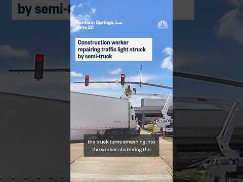 Construction worker repairing traffic light struck by semi-truck