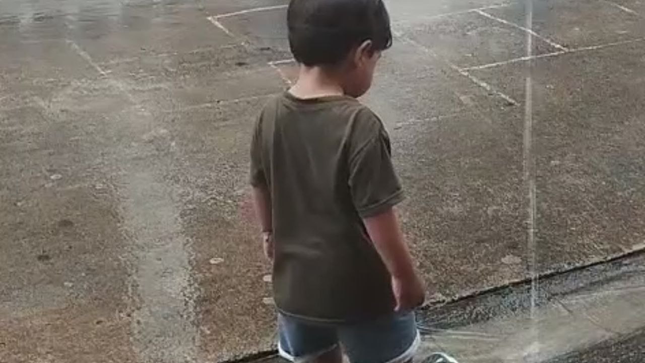 Child chases flip-flops after water current sweeps them away